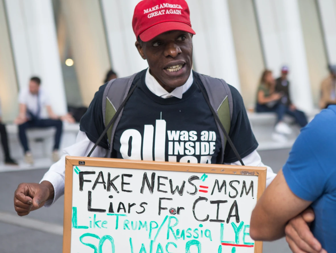 An image of a protestor with a sign referencing fake news.