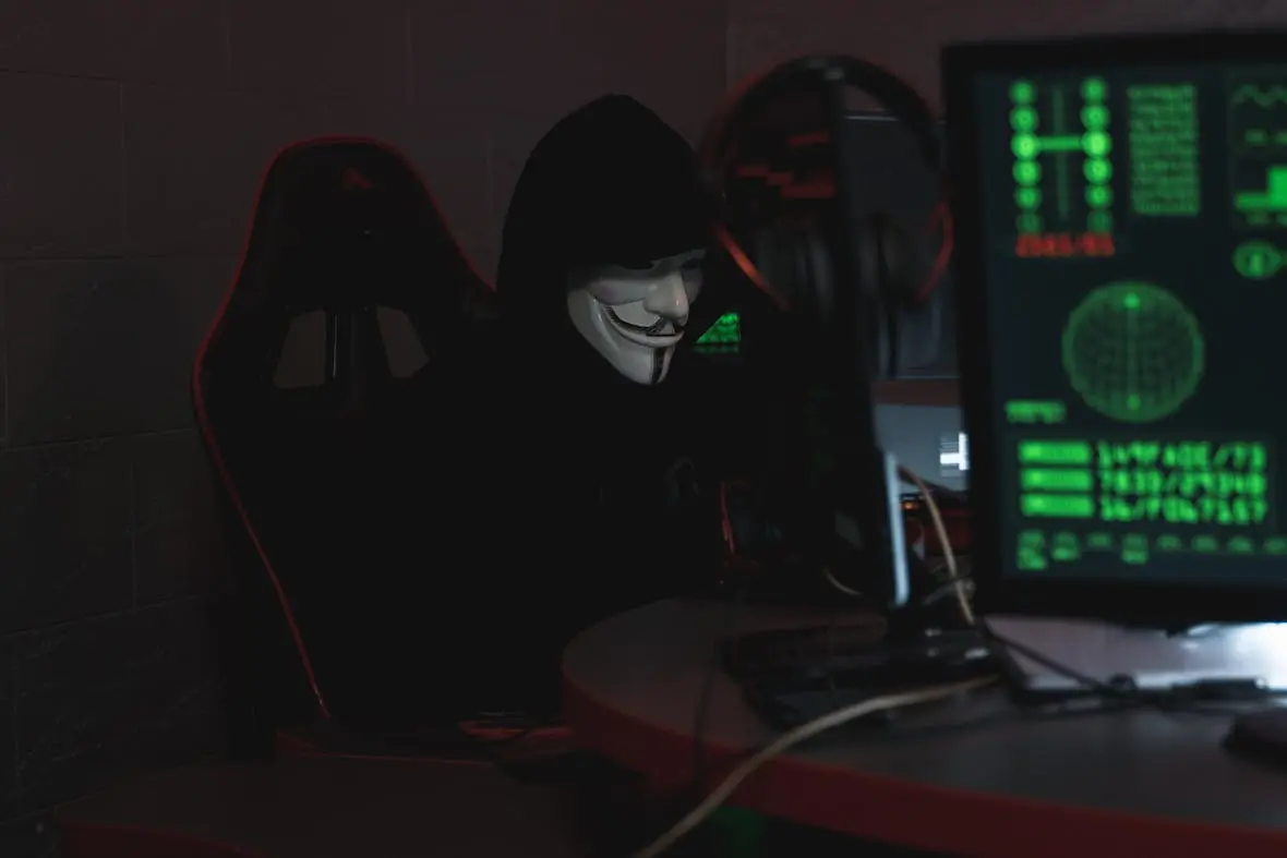 A photo of a hacker in a dark hood and mask.